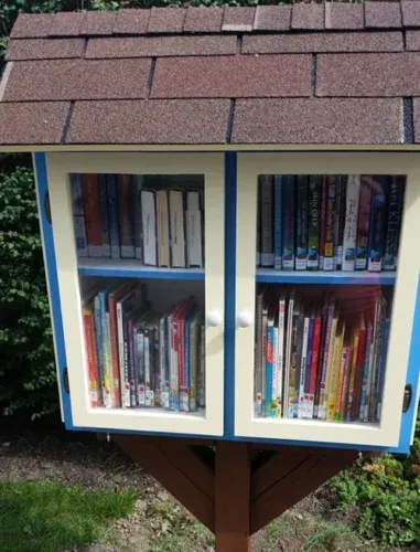 The Little Free Library: a small white wooden cabinet on a post, its glass door showing shelves of books