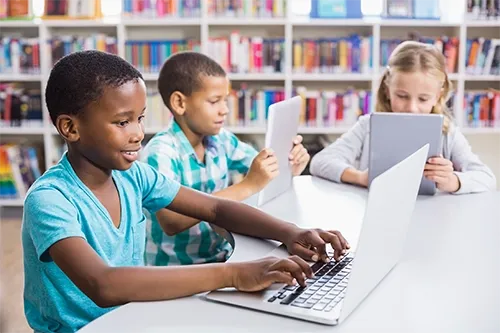 Children using laptops together at a library table
